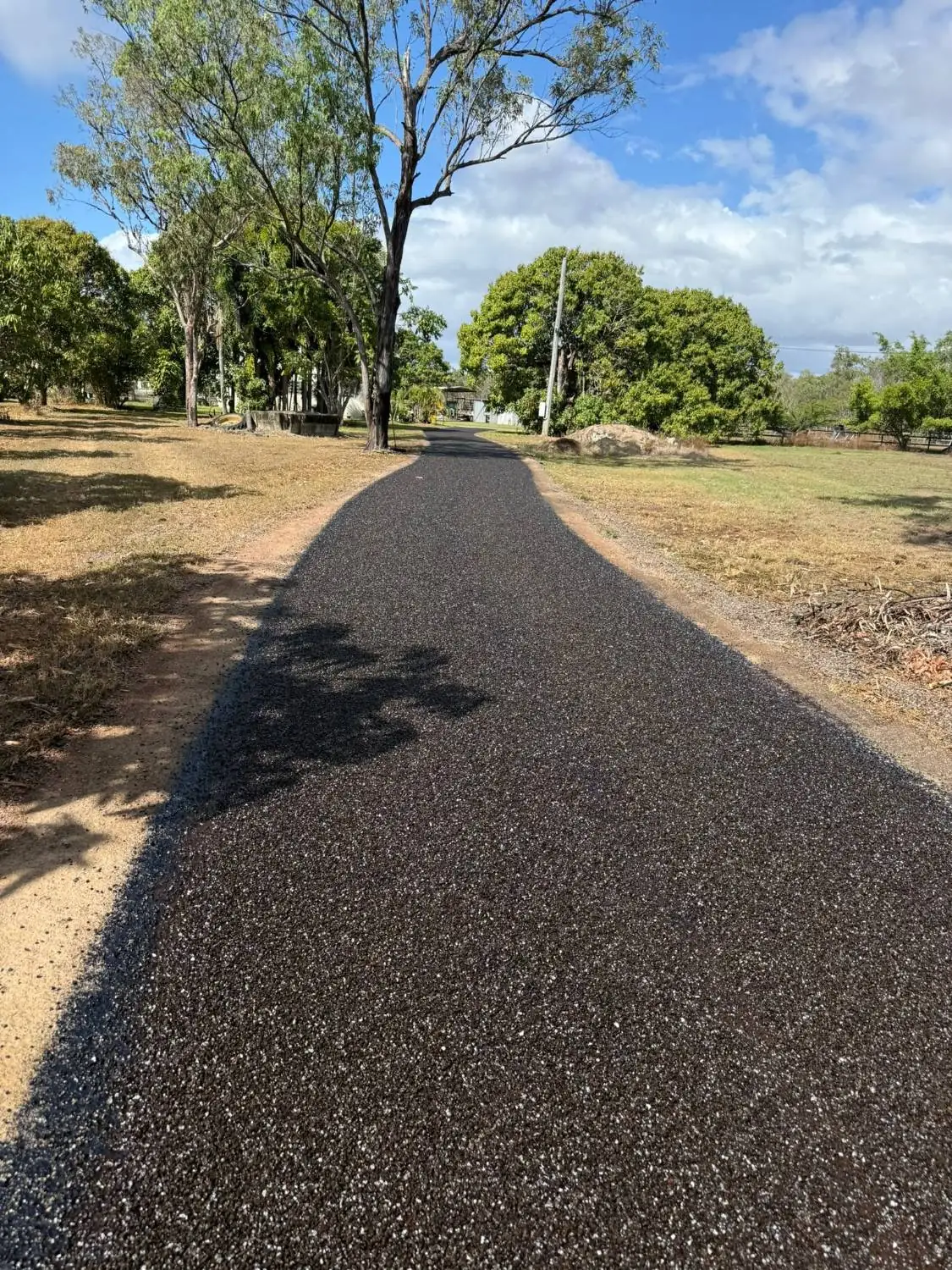 Freshly sealed driveway extending across a large rural acreage